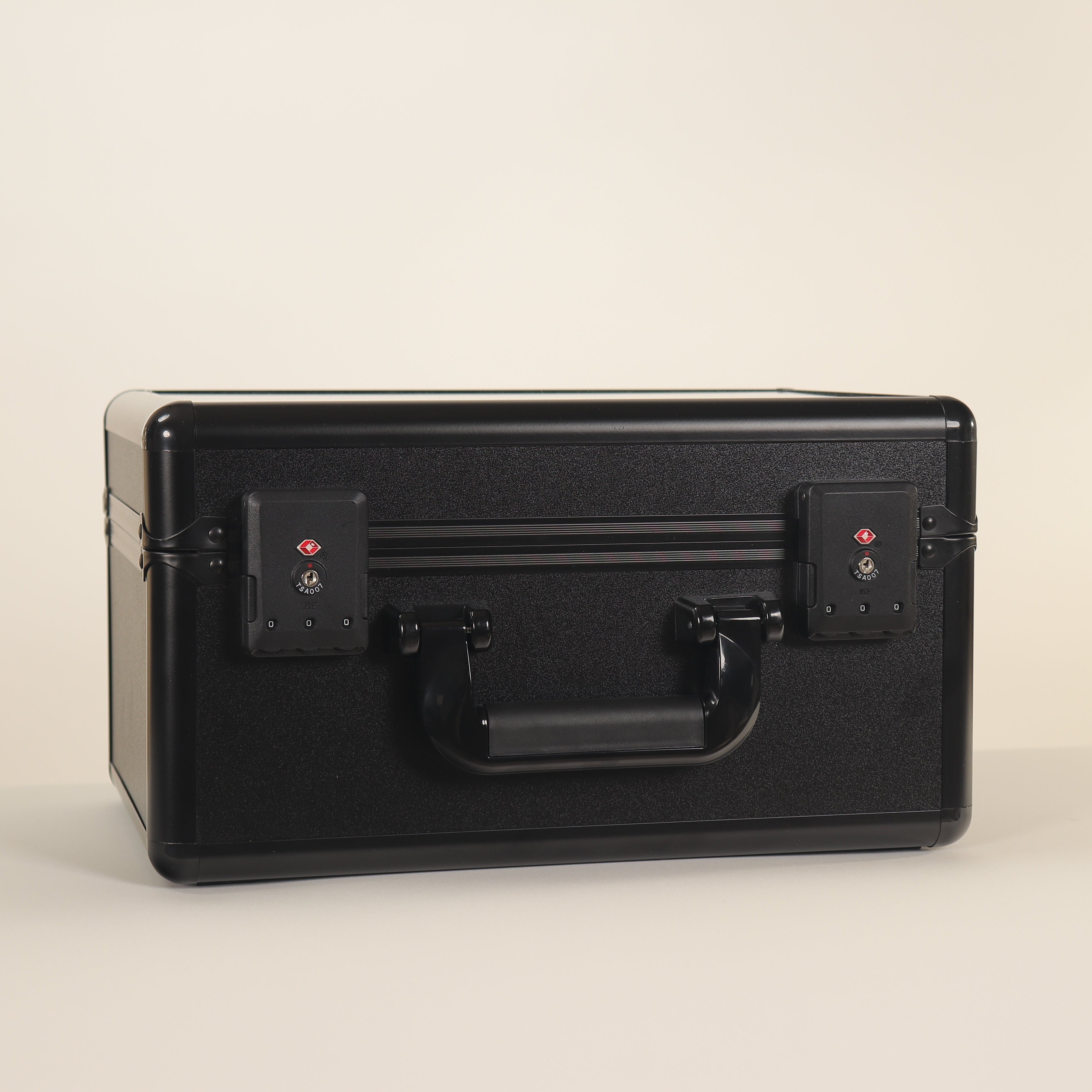 Black suitcase with a handle on a beige background