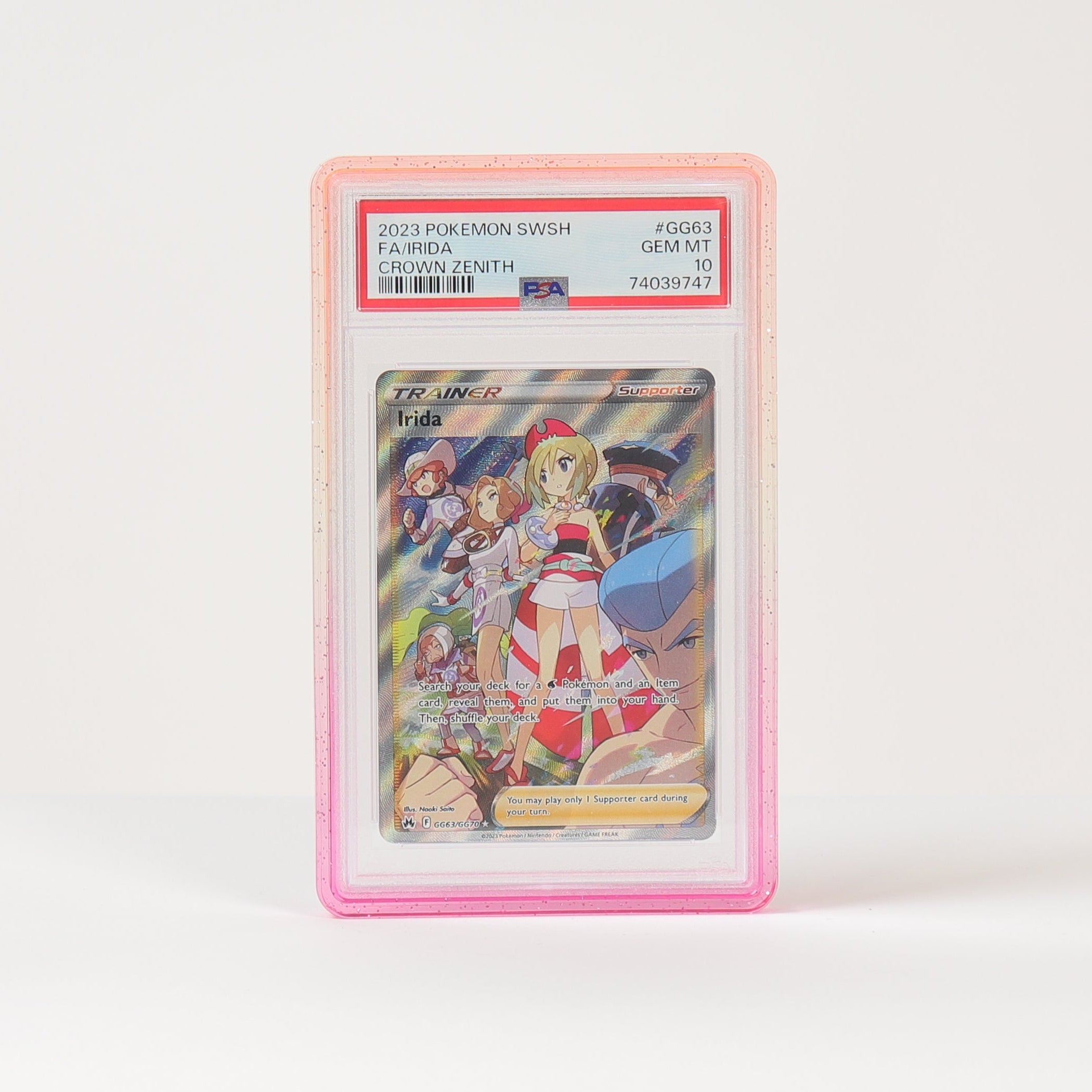 A graded holographic Pokémon card in a pink PSA-style slab, standing upright on a white surface against a white background.